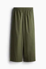 Pantalón de algodón color verde militar, de corte ancho y tobillero. Presenta cintura elástica fruncida y piernas amplias.