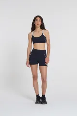 Top deportivo negro con tirantes blancos regulables, escote medio y compresión media.