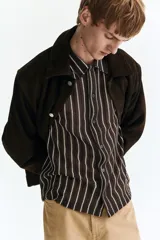 Camisa de manga corta en punto texturizado, de corte estándar, con diseño a rayas verticales en color marrón y blanco, cuello y cierre frontal de botones.