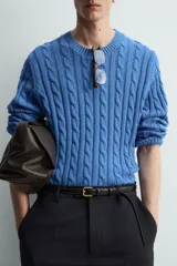 Jersey de punto de algodón, color azul, con cuello redondo y manga larga. Presenta un tejido con estructura de trenzas verticales a lo largo de todo el cuerpo y mangas.