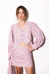 Camisa de popelina con diseño de rayas verticales en tonos rosado, celeste y marrón. Presenta escote en V, cierre frontal con botones dorados, corte asimétrico en el bajo y mangas largas abullonadas.