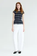 Saco ajustado en punto fino suave, color negro con rayas horizontales blancas. Modelo con cuello redondo, manga japonesa, botones hasta la cintura y peplum acampanado.