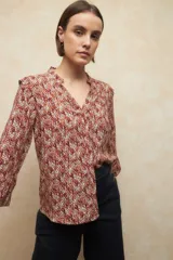 Camisa de manga larga con estampado geométrico en tonos azul y blanco, escote en V con detalle de volado en el cuello, cierre frontal con botones a tono y puños elásticos.