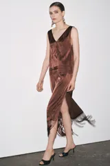 Vestido midi marrón con bordados florales y geométricos en el frente, escote redondo, mangas sisa, tejido plisado y flecos en el ruedo.