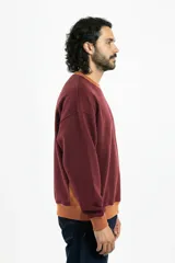 Buzo bordó de corte oversize con cuello redondo, puños y cintura acanalados en color marrón. Presenta paneles laterales con vivo blanco y logo Vernal bordado en el pecho.