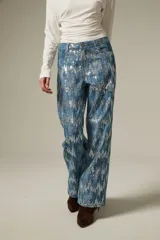 Pantalon de jean recto con acabado brillante de lentejuelas plateadas sobre base azul, de tiro medio.