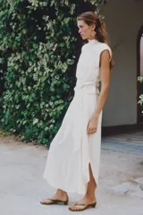 Pantalón fluido de tiro alto en color blanco, con pinzas delanteras, cintura elástica en la espalda y perneras anchas con aberturas laterales pronunciadas.