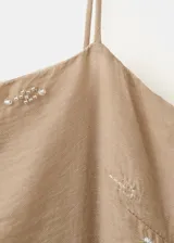 Vestido corto recto en color beige, con tirantes finos y escote recto. Presenta un delicado diseño bordado floral en hilo metalizado y cuenta con un bolsillo frontal superpuesto a la altura de la cadera.
