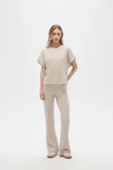 Pantalón acampanado de poliéster y lurex, color beige, de tiro alto y corte holgado.