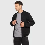 Chaqueta bomber color negro de lona de algodón, con cierre frontal, bolsillos laterales, bolsillo vertical con cierre en el pecho y puños, cuello y ruedo de rib elástico.