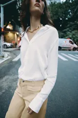 Camisa de cuello solapa y escote en pico, color marrón oscuro, de manga larga con puños anchos y cierre frontal con botones.