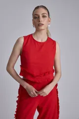 Conjunto de dos piezas color rojo, compuesto por un top sin mangas con detalle de volado fruncido en el bajo y un pantalón ancho de tiro alto con volados largos a lo largo de las costuras laterales exteriores.