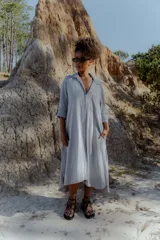 Vestido camisero midi color gris claro, de corte amplio, con cuello camisero, mangas 3/4 y cierre frontal con botones.