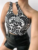 Top negro brillante de un solo hombro con abertura en el hombro izquierdo.