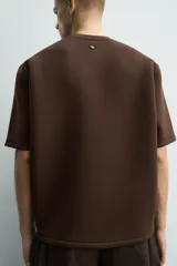 Sudadera de manga corta con corte relajado, confeccionada en tejido técnico compacto de algodón con elasticidad. Presenta cuello redondo y detalle de tacha metálica en la espalda.