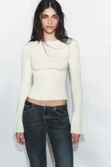 Jersey de punto pointelle color blanco, con cuello redondo y mangas largas acabadas en evasé.