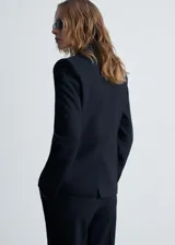 Chaqueta de corte recto y diseño estructurado con estampado de raya diplomática. Presenta cuello con solapa, cierre frontal de dos botones, manga larga con puños abotonados, un bolsillo de ribete en el pecho y dos bolsillos laterales con solapa.