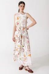 Vestido largo confeccionado en popelina blanca con un estampado lúdico de frutas y sus nombres. Posee cuello redondo, hombros de corte semi-halter y lazos frontales para ajustar en la cintura.