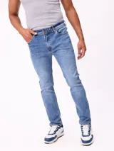Jean de corte slim fit en color azul lavado, con diseño clásico de cinco bolsillos, cierre frontal con botón y costuras en contraste.