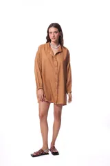 Vestido camisero color marrón claro, de corte oversized, manga 3/4 con puños elásticos y cierre frontal con botones a tono.