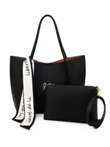 Set de cartera tipo tote bag negra con textura granulada y sobre a juego con correa de muñeca. Incluye un pañuelo decorativo blanco con inscripciones negras atado a una de las asas.