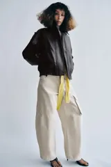 Chaqueta bomber de efecto piel en color marrón oscuro, con cuello solapa, cierre frontal con cremallera y botones, bolsillos delanteros, trabillas en los hombros y puños y bajo elásticos.