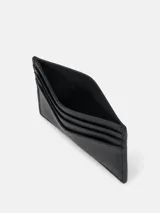 Tarjetero negro de cuero con seis ranuras para tarjetas y logo de Calvin Klein Jeans grabado en la parte delantera.