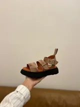 Sandalias de cuero color beige con plataforma de goma negra, tiras anchas con hebillas ajustables y tira trasera con velcro.