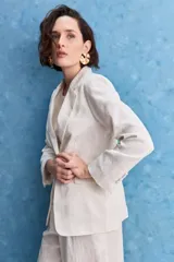 Blazer color beige claro, de corte clásico con solapa, cierre de un botón y bolsillos delanteros de vivo.