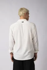 Camisa de manga larga con cuello clásico y cierre frontal de botones. Presenta un calce relajado y una textura liviana.