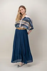 Pollera larga de color marrón, confeccionada en tela liviana con textura sutil y diseño plisado. Incluye un cinto rústico trenzado.