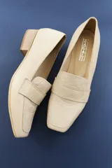 Mocasines de cuero vacuno color beige con textura efecto cocodrilo, punta cuadrada y taco bajo.