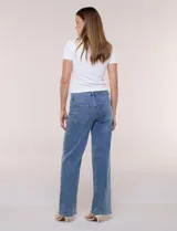 Pantalón jean denim de tiro medio y calce holgado, con pierna de corte recto y lavado con sutil desgaste en costuras. Cuenta con bolsillos funcionales frontales, recortes verticales y cierre frontal con cremallera y botón metálico.