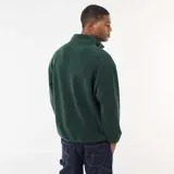 Sweater de polar verde con cuello alto tipo camionero y cierre frontal con botones a presión. Diseño de manga larga con puños elásticos.