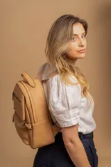 Mochila de cuero sintético color suela, con compartimento principal amplio, bolsillo frontal con cierre y correas ajustables.