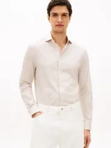 Camisa de manga larga Tommy Hilfiger con diseño de rayas beige y blancas, cuello con tecnología Flex y cierre frontal con botones.