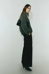 Pantalón sastrero negro de corte acampanado, con cierre, botón oculto y corchetes. Incluye bolsillos al bies y bolsillos traseros ribeteados, con pliegues en la parte delantera y trasera de las piernas.