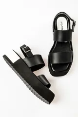 Sandalias negras de cuero con plataforma blanca y hebilla metálica.