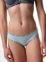 Bombacha tipo bikini de tiro medio confeccionada en algodón acanalado blanco, con bordes terminados en ribete con estampado animal print.