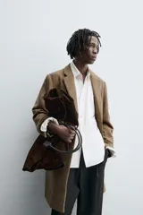 Abrigo de corte regular fit confeccionado en tejido compacto con mezcla de lana. Presenta cuello con solapas de muesca, cierre frontal de botonadura, bolsillos de vivo en la cadera y abertura central en la espalda.