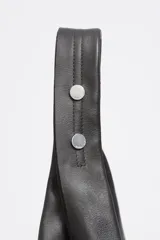 Bolso de hombro de tamaño maxi confeccionado en piel vacuna con acabado brillante. Presenta una estructura blanda, asa de hombro integrada y logo metálico de la marca en la parte inferior. Incluye bolsillo interior y cierre de cordón.