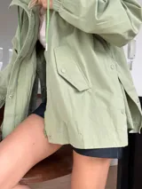 Campera verde claro de corte holgado y mangas largas con puños elásticos. Cierre frontal con botones a presión.