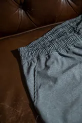 Short deportivo gris melange con cintura elástica y aberturas laterales para mayor movilidad. Presenta un logo de alas estampado en color azul en la parte inferior izquierda.