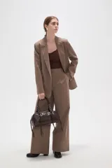 Bolso tipo bowling color negro de poliuretano, con doble asa corta decorada con argollas y tiritas colgantes en los laterales.