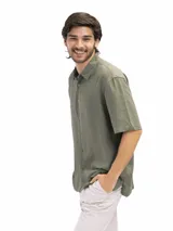 Camisa de manga corta color verde oliva, confeccionada en lino y viscosa, con cuello clásico y cierre frontal con botones. Corte suelto y estilo casual.