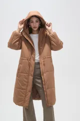 Campera larga tipo parka acolchada color negro, con capucha desmontable, cierre frontal con botones a presión, bolsillos laterales y cordón ajustable en la cintura.