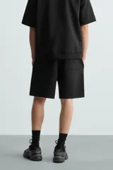 Bermuda de algodón color beige claro, corte relajado (relaxed fit), con cintura elástica ajustable mediante cordón y bolsillos laterales y trasero de plastrón.