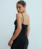 Vestido midi de satén negro con escote en V profundo, breteles finos ajustables y corte recto con caída fluida.