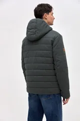 Campera de gabardina capitoneada con interior forrado en nylon. Presenta capucha fija, bolsillos frontales en el pecho con solapa y bolsillos laterales con cierre. Cuenta con cierre frontal central.