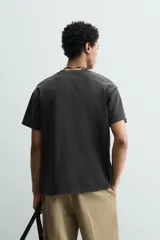 Camiseta de corte boxy fit, con cuello redondo y manga corta. Presenta un acabado irregular con efecto lavado que le otorga un aspecto vintage.